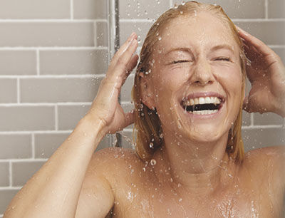 Frau die unter der Dusche steht und lacht